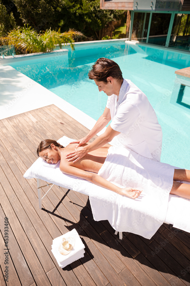 Obraz premium Woman receiving massage poolside at spa
