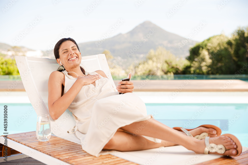 Woman listening to mp3 player at poolside