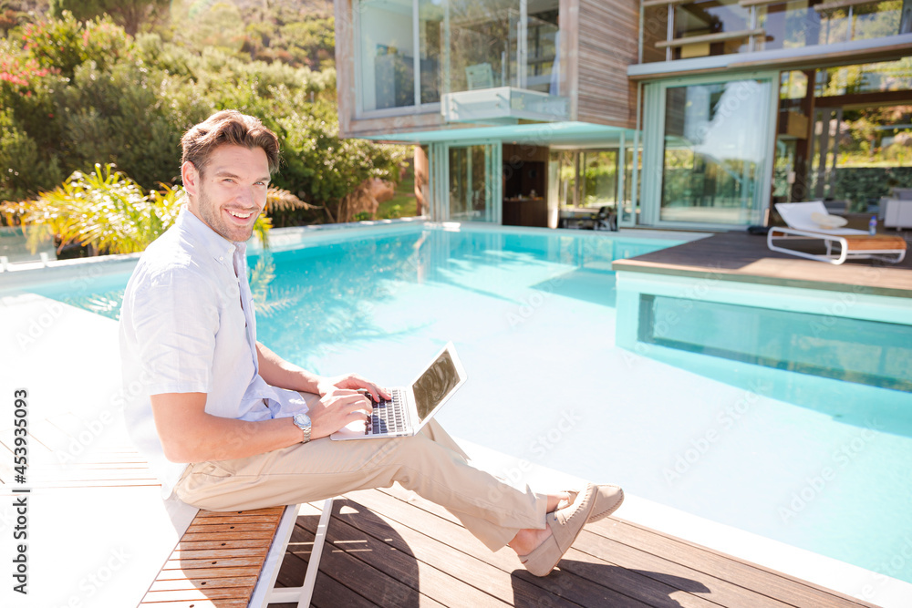 Man using laptop at poolside