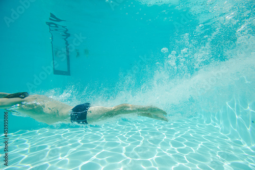 Man swimming underwater in pool