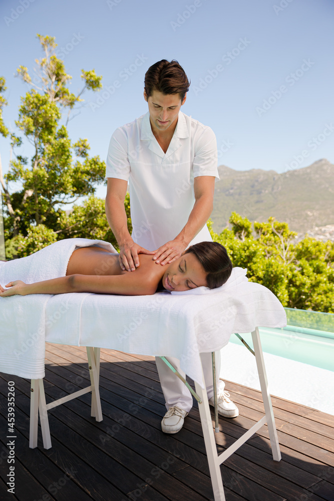 Woman receiving massage poolside at spa Woman receiving massage poolside at spa