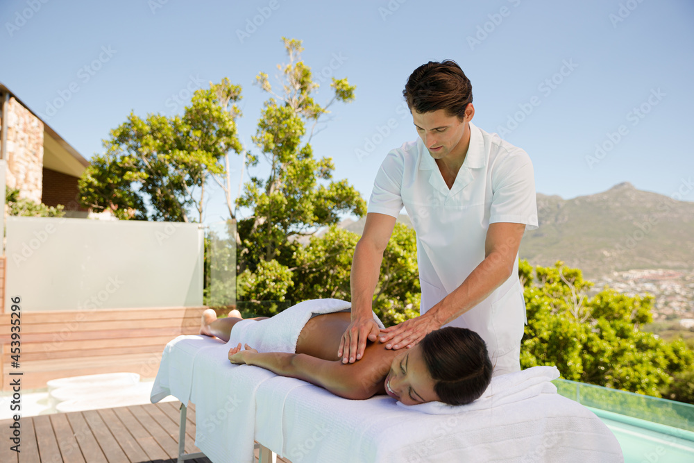 Woman receiving massage poolside at spa