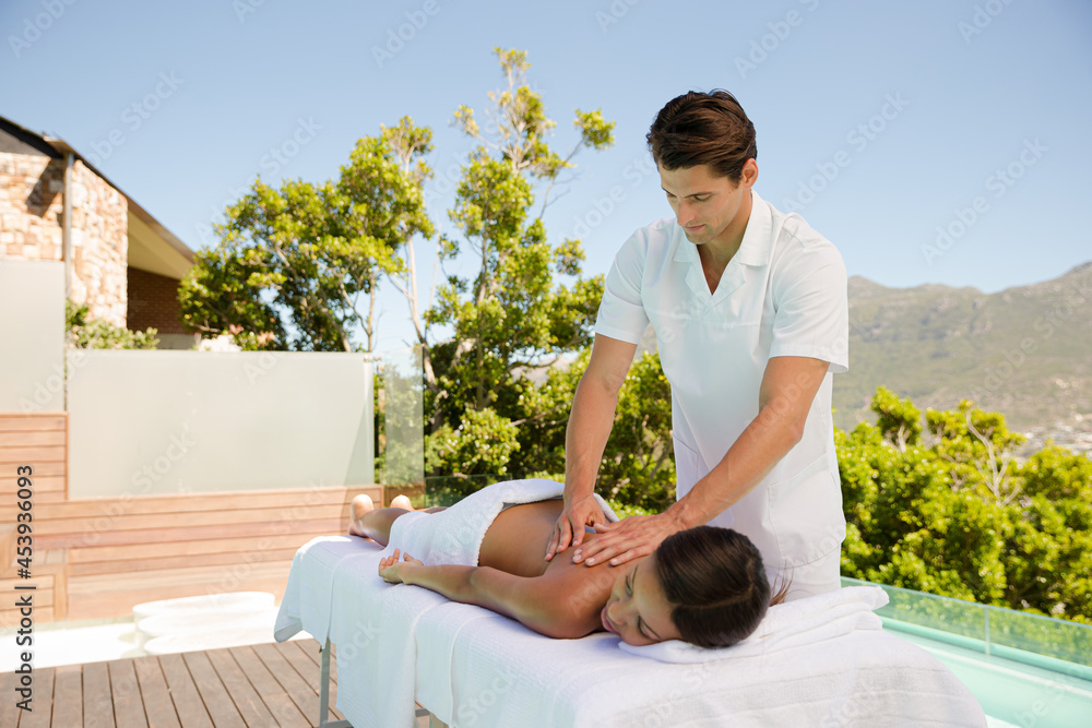 Woman receiving massage poolside at spa Woman receiving massage poolside at spa