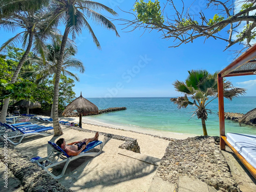 Man relaxing in a tropical beach with turquoise water in Baru, Islas del Rosario, Cartagena de Indias, Colombia.