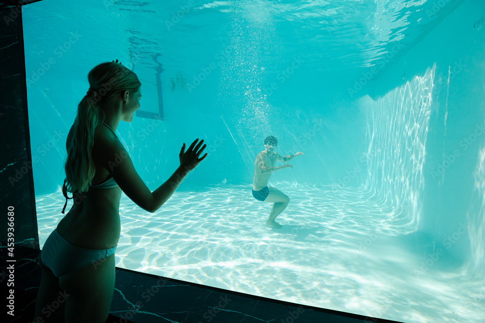 Woman watching boyfriend underwater in swimming pool
