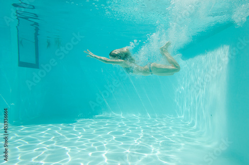 Woman swimming underwater in pool