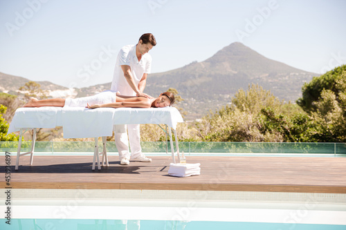 Woman receiving massage poolside at spa © KOTO
