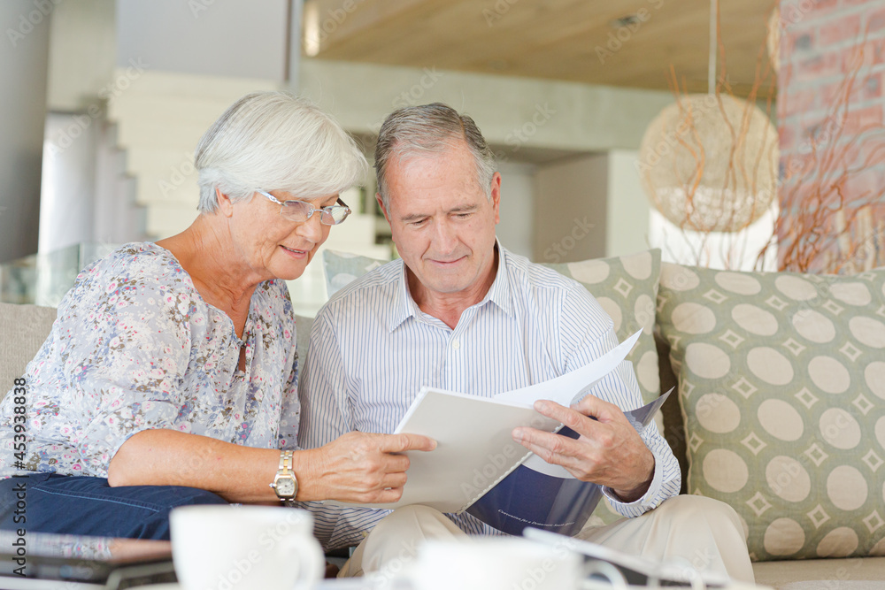 Couple examining blueprints on sofa Couple examining blueprints on sofa