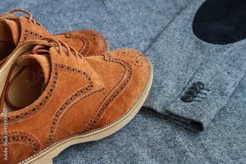 A pair of brown suede derby shoes on tweed blazer background. Top view.