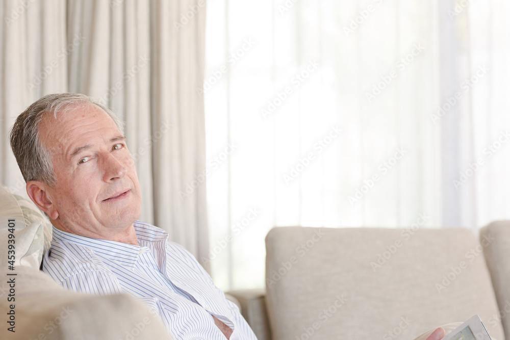 Older man using tablet computer on sofa Older man using tablet computer on sofa
