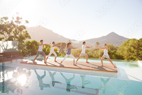 People practicing yoga at poolside