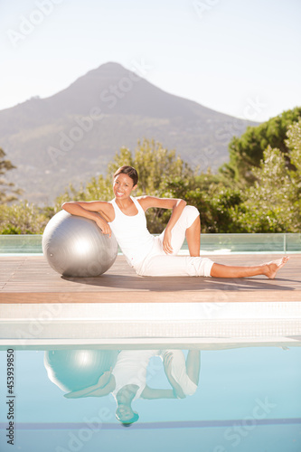 Woman stretching over fitness ball at poolside © KOTO