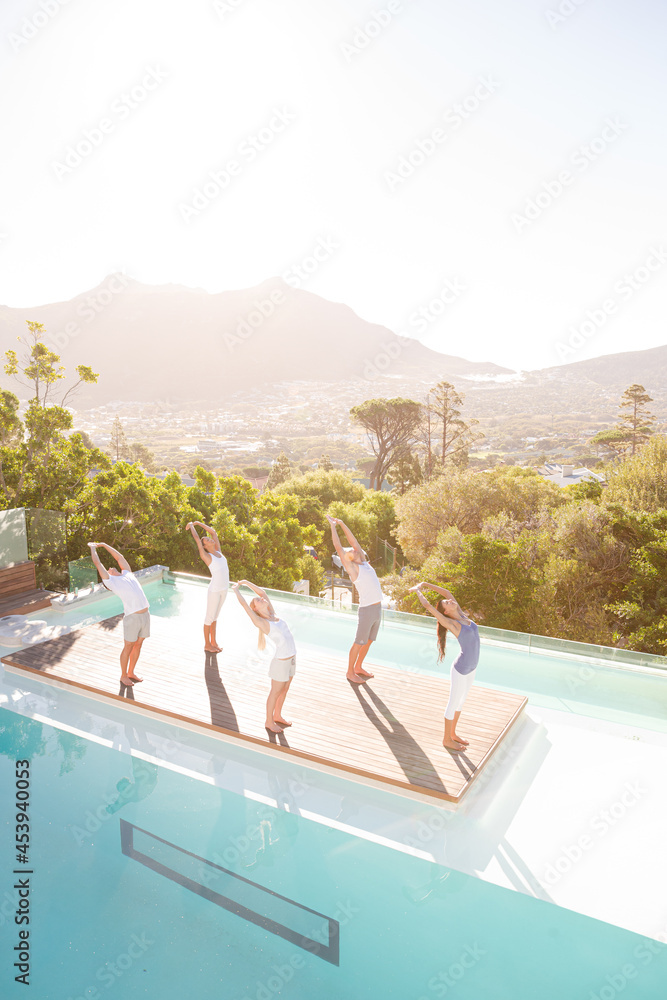 Obraz premium People practicing yoga at poolside