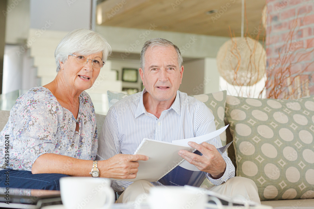 Couple examining blueprints on sofa Couple examining blueprints on sofa