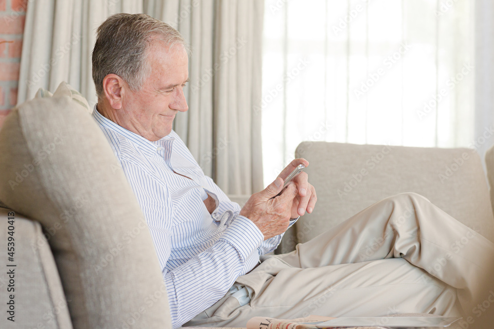 Older man using cell phone on sofa