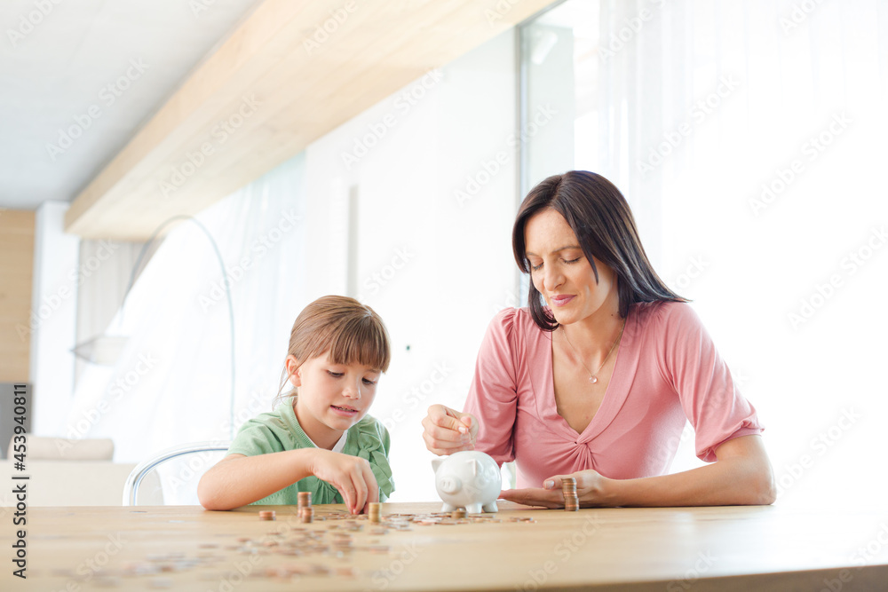 Mother and daughter filling piggy bank Mother and daughter filling piggy bank