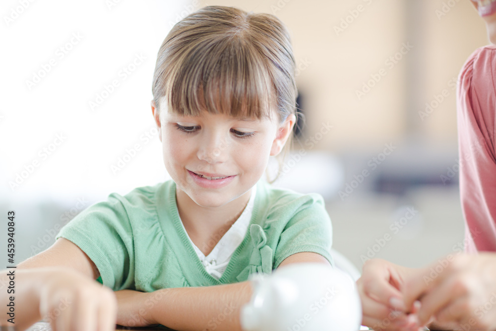 Girl filling piggy bank on counter Girl filling piggy bank on counter