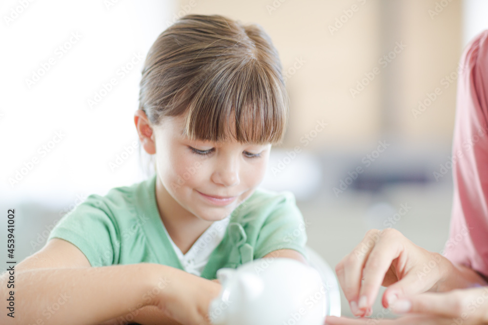 Girl filling piggy bank on counter Girl filling piggy bank on counter