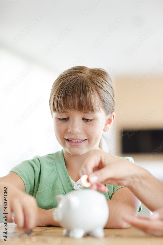 Girl filling piggy bank on counter Girl filling piggy bank on counter