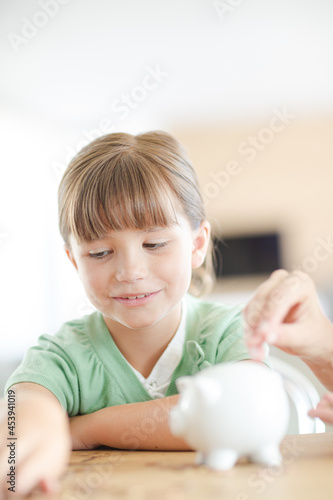 Girl filling piggy bank on counter