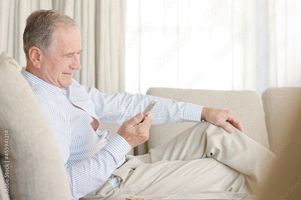 Older man using cell phone on sofa Older man using cell phone on sofa