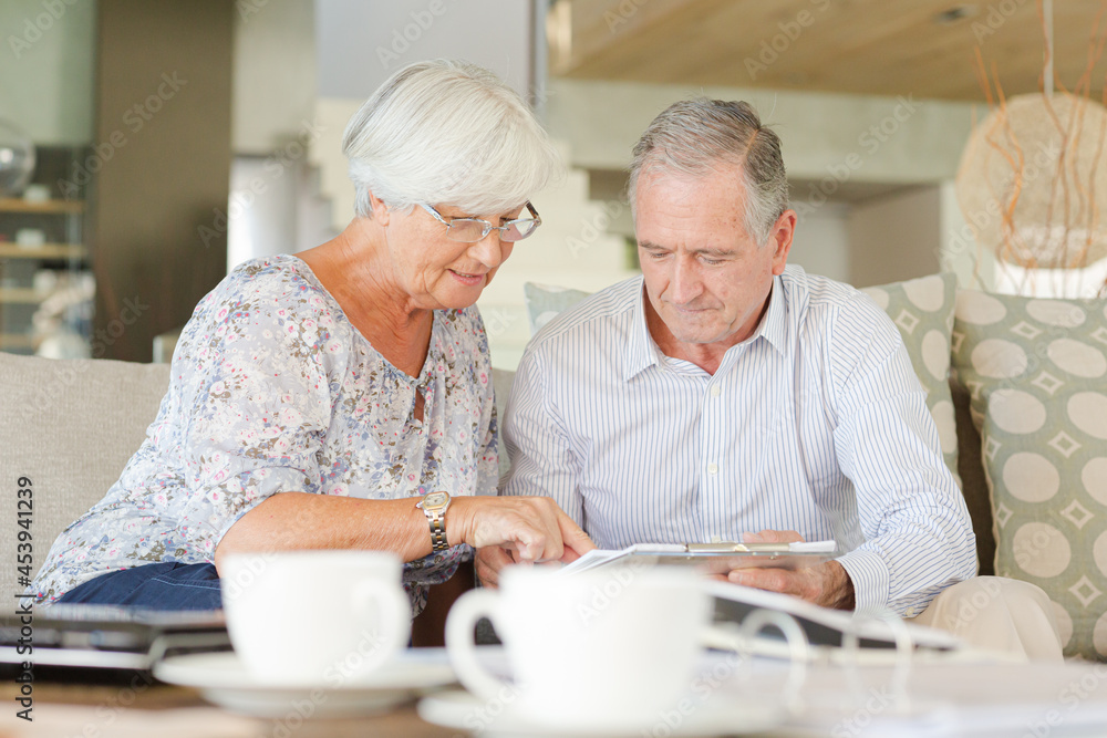 Couple examining blueprints on sofa Couple examining blueprints on sofa
