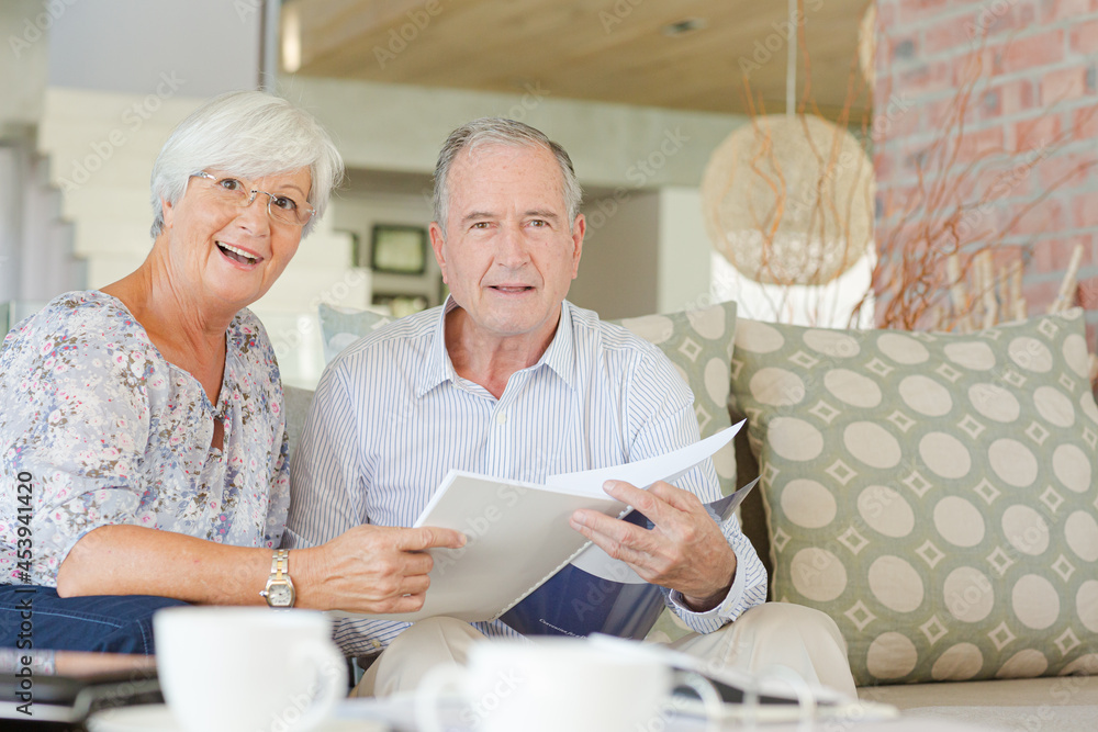 Couple examining blueprints on sofa Couple examining blueprints on sofa