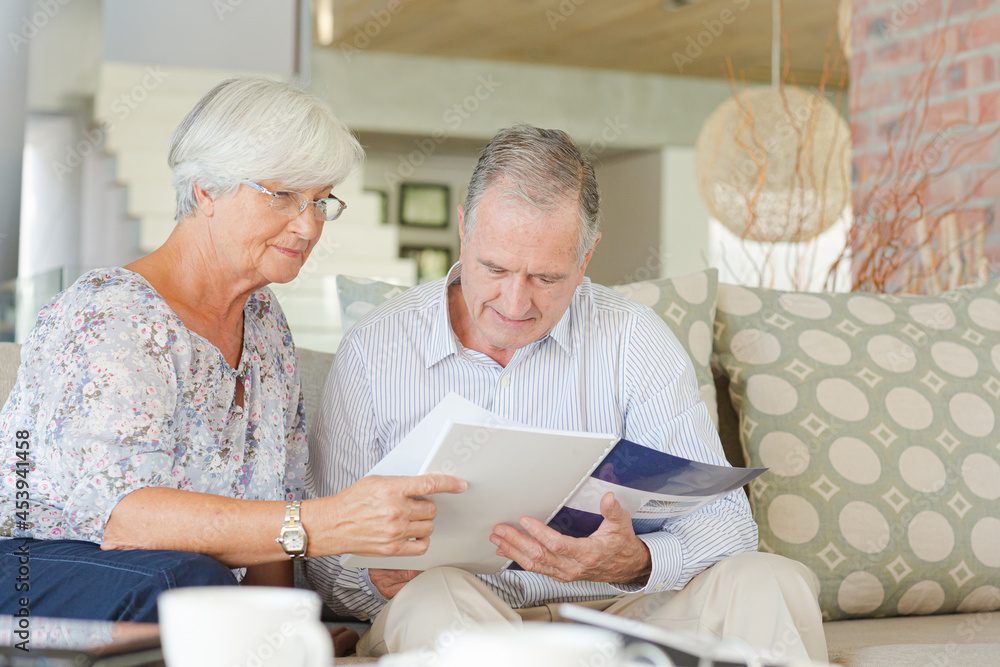 Couple examining blueprints on sofa Couple examining blueprints on sofa