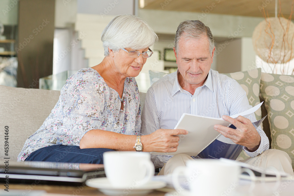Couple examining blueprints on sofa Couple examining blueprints on sofa