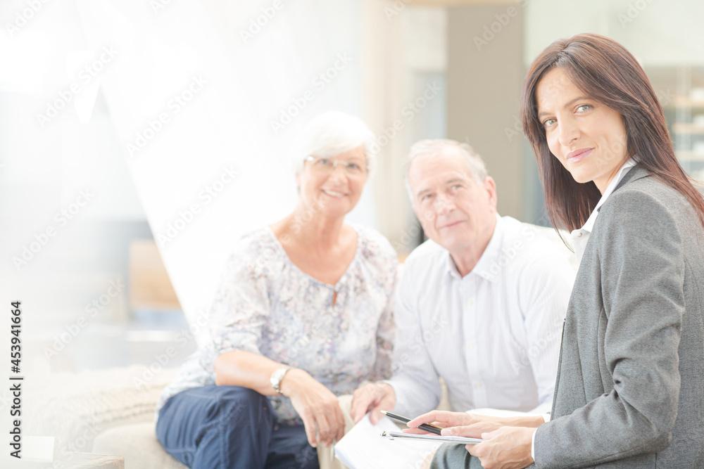 Financial advisor smiling with couple on sofa Financial advisor smiling with couple on sofa