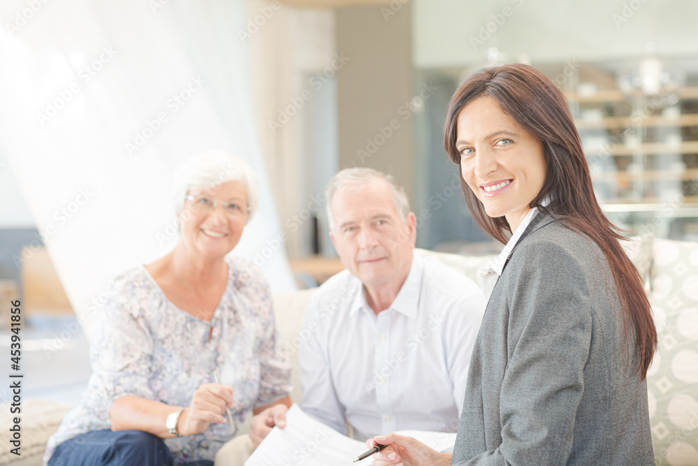 Financial advisor smiling with couple on sofa Financial advisor smiling with couple on sofa