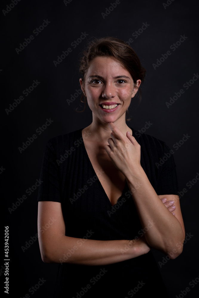 A young beautiful woman surprised by something in a studio shot in black dress and background