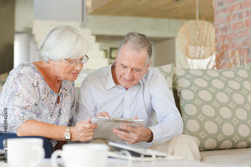 Couple examining blueprints on sofa Couple examining blueprints on sofa