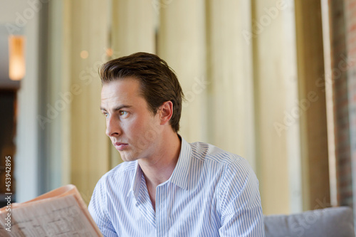 Man reading newspaper on sofa