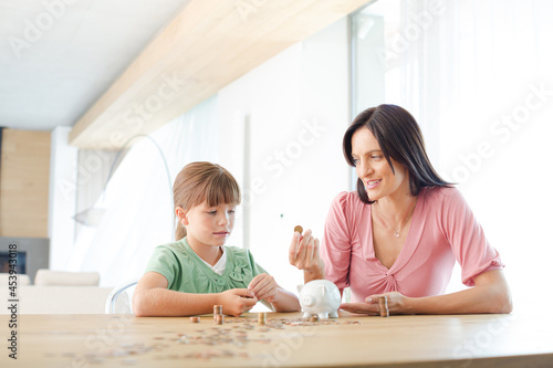 Photos Mother and daughter filling piggy bank