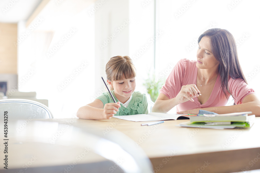 Mother helping daughter with homework Mother helping daughter with homework