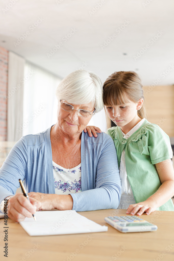 Older woman and granddaughter using calculator Older woman and granddaughter using calculator
