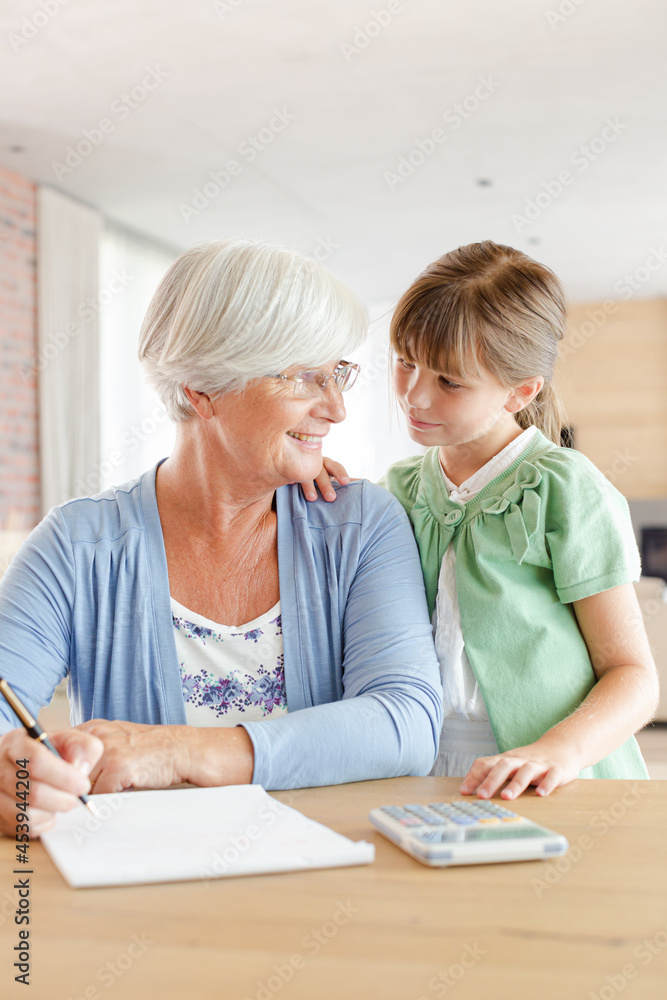 Older woman and granddaughter using calculator Older woman and granddaughter using calculator