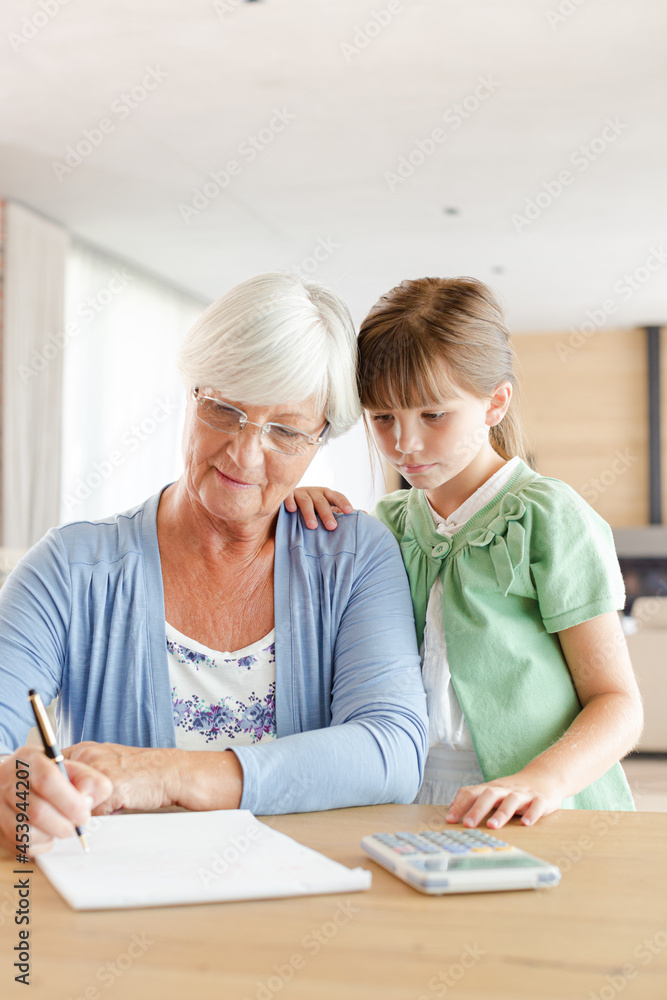 Older woman and granddaughter using calculator Older woman and granddaughter using calculator
