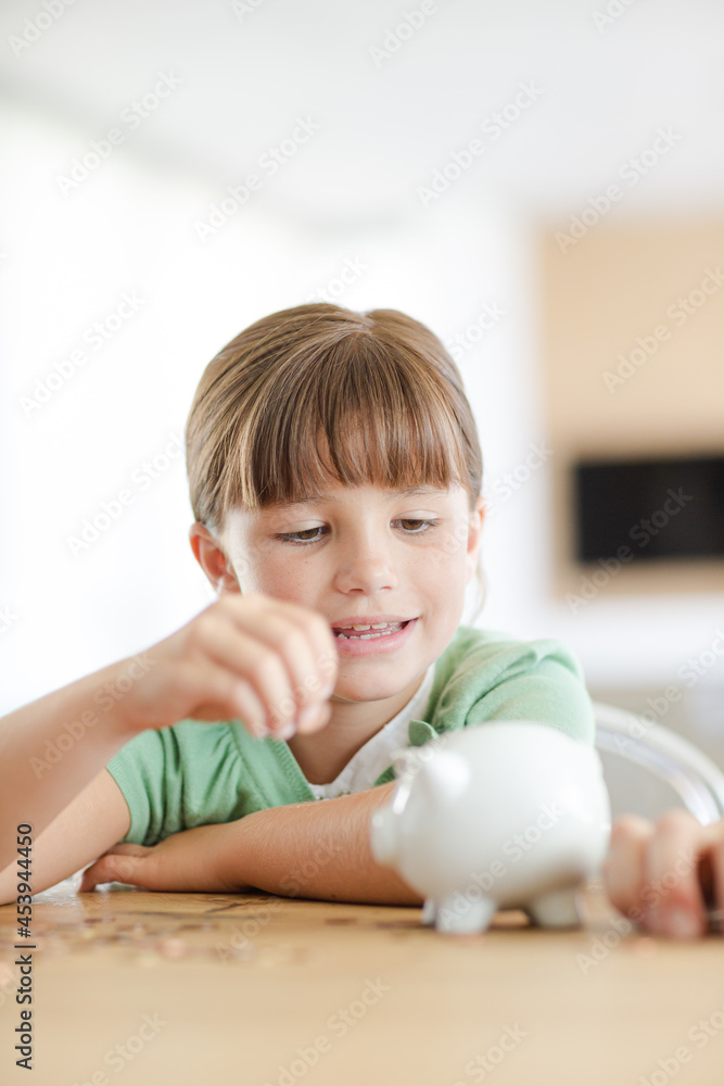 Girl filling piggy bank on counter