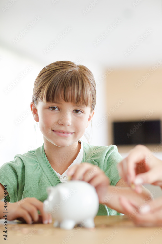 Girl filling piggy bank on counter Girl filling piggy bank on counter