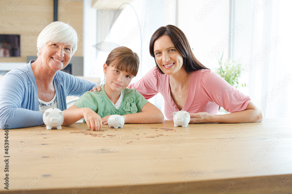 Three generations of women filling piggy bank Three generations of women filling piggy bank