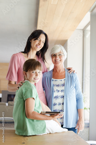 Three generations of women posing in kitchen, smiling © KOTO