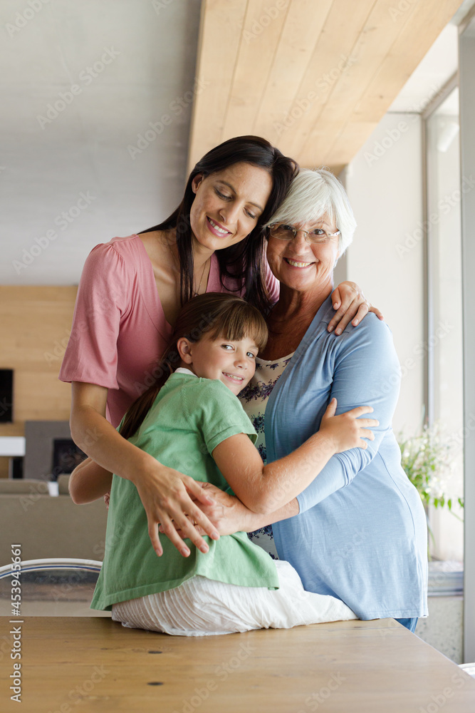 Three generations of women hugging in kitchen Three generations of women hugging in kitchen
