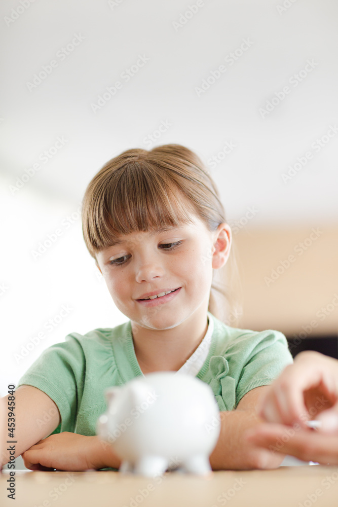 Girl filling piggy bank on counter Girl filling piggy bank on counter