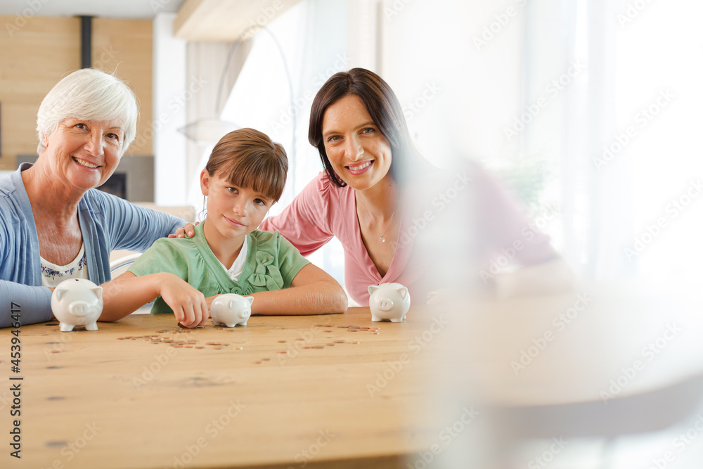 Three generations of women filling piggy bank Three generations of women filling piggy bank