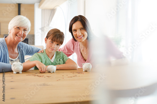 Three generations of women filling piggy bank