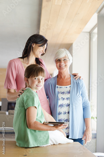 Three generations of women posing in kitchen, smiling
