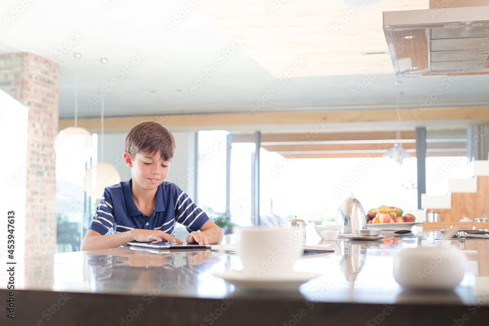 Boy using tablet computer in kitchen Boy using tablet computer in kitchen
