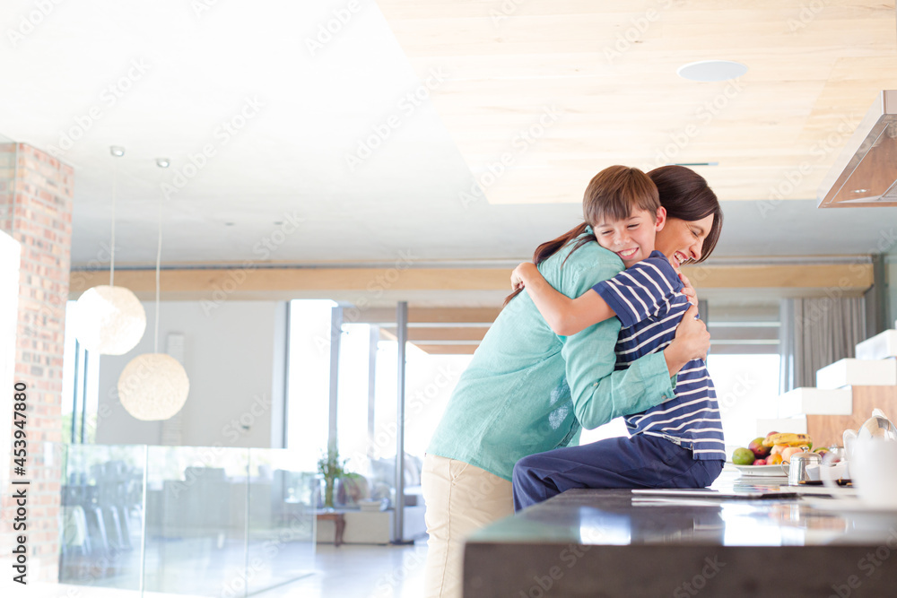 Mother and son hugging in kitchen Mother and son hugging in kitchen